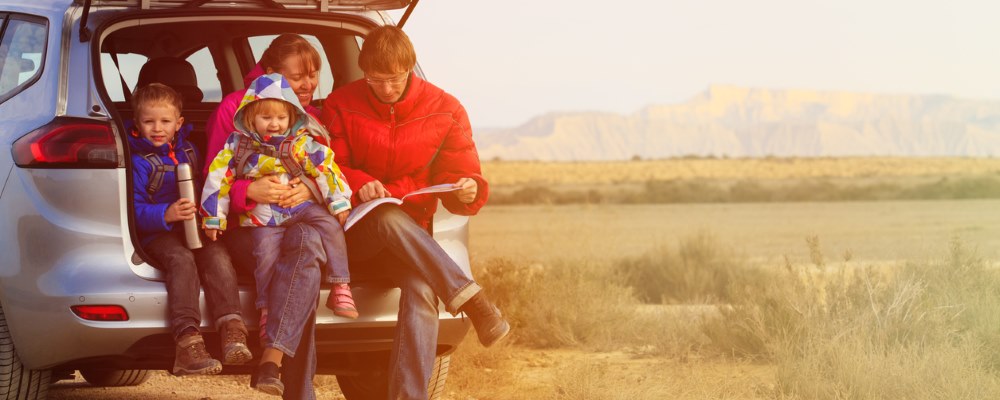 family sitting in boot of a car outdoors